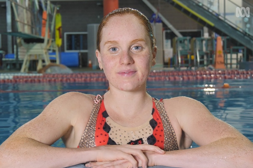 A young woman wearing her competition swimsuit  standing in the pool.