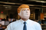 A man poses in a Donald Trump mask.