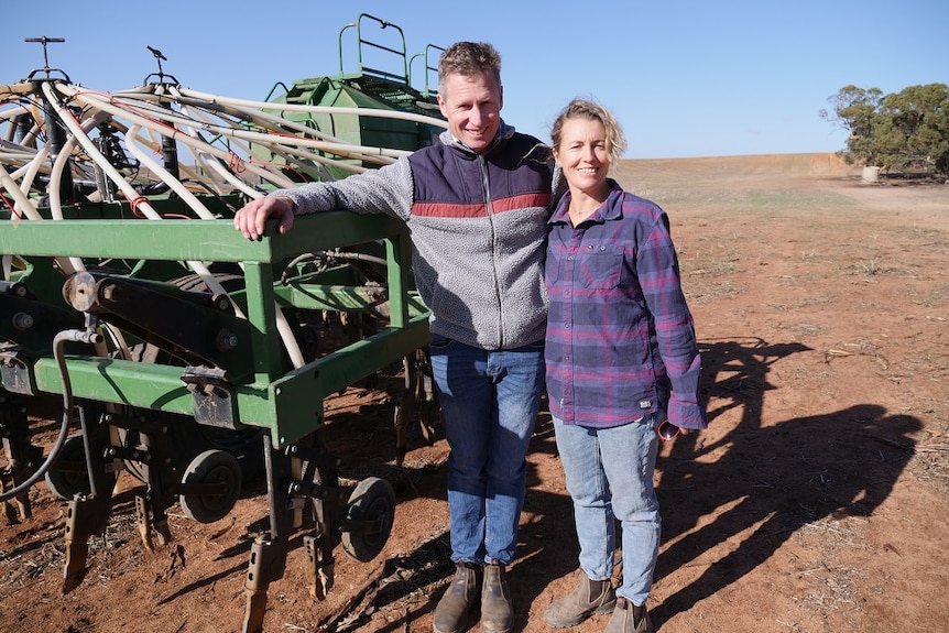 Man and woman stand by a machine that sows seed direct into the soil