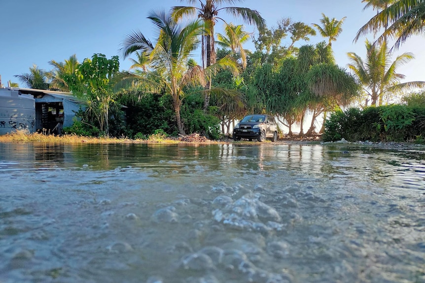 Water bubbles as a car passes in the background during flooding from a king tide in early 2024.