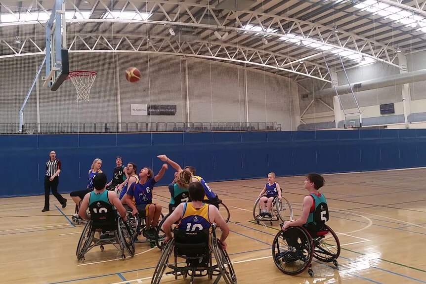 wheelchair bound players playing basketball on a court.