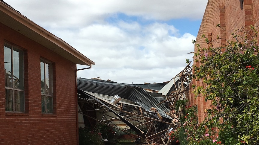 Pile of tin and metal on the ground at the back of a red brick building