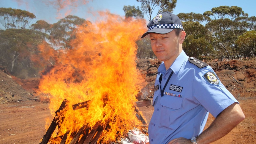 Inspector Hamish McKenzie standing near the huge fire of burning drugs and pallets at the Coolgardie rubbish tip.
