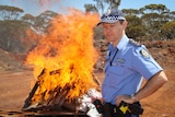 Inspector Hamish McKenzie standing near the huge fire of burning drugs and pallets at the Coolgardie rubbish tip.