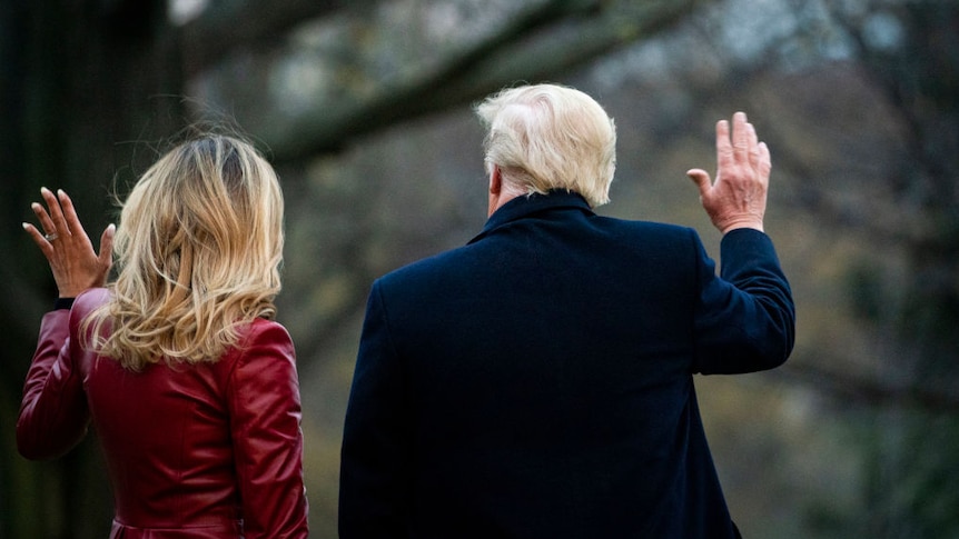 A rear shot of Melania and Donald Trump waving as they walk towards the helicopter.