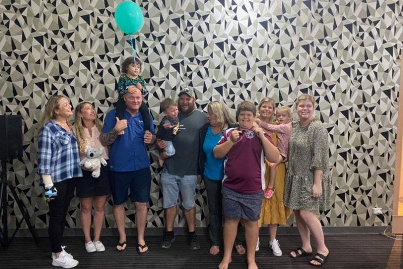 A family group featuring several young kids, all smiling.