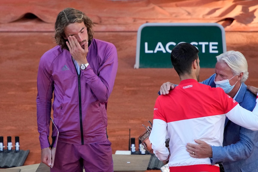 Novak Djokovic receives the French Open trophy from Bjorn Borg, as his beaten opponent brushes back a tear.