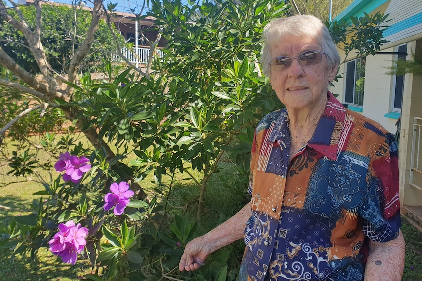 Lady in glasses standing in front of tree with purple flowers