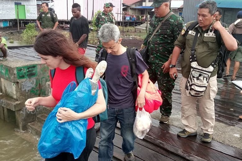 Two BBC journalists being escorted out of Papua by military personnel