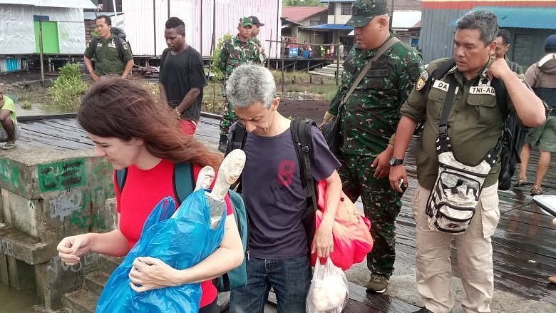 Two BBC journalists being escorted out of Papua by military personnel