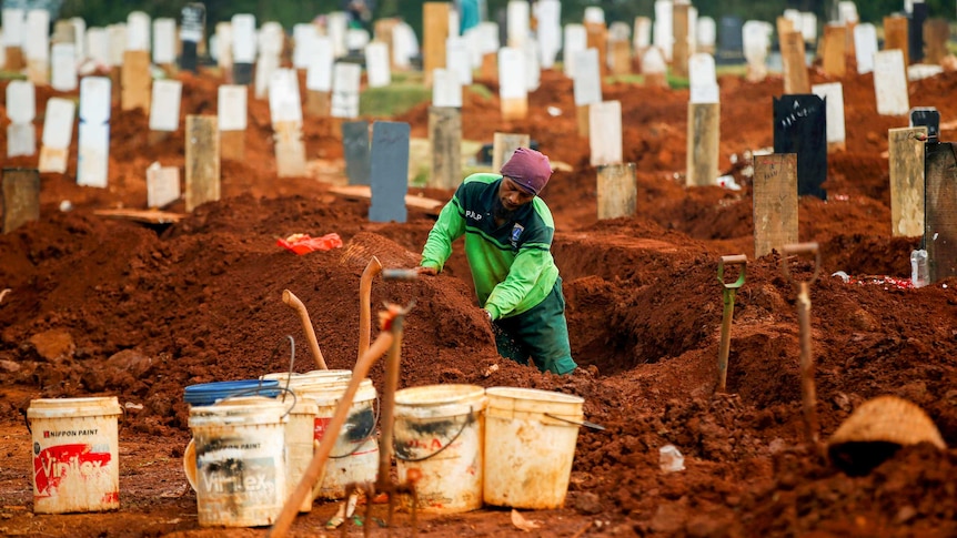 A gravedigger standing in a plot surrounded by gravestones
