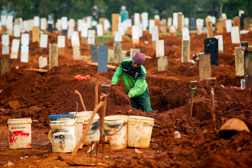 A gravedigger standing in a plot surrounded by gravestones