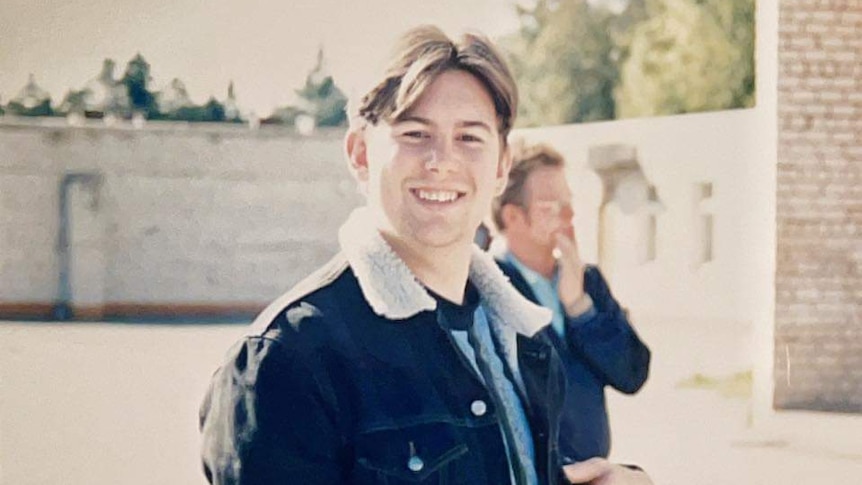 Young man holding bible standing in cement outdoor area, 1995.