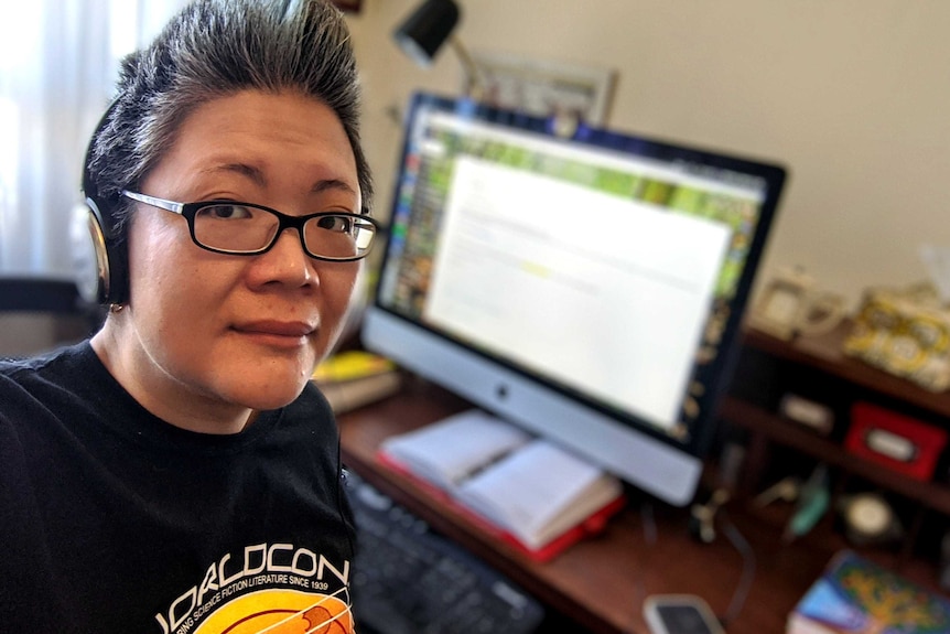 Adeline Teoh wears headphones while at her desk, for a story about noise and working from home.