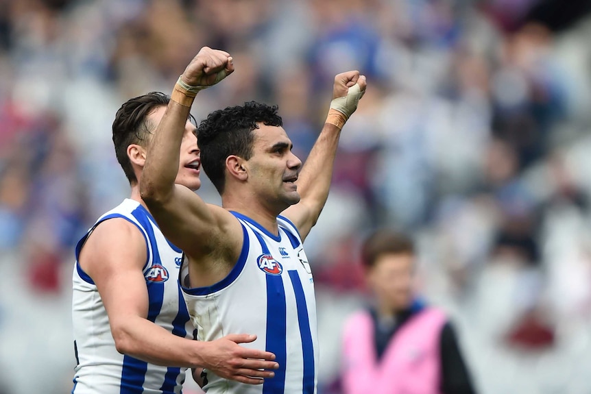 Two North Melbourne AFL players celebrate a goal.