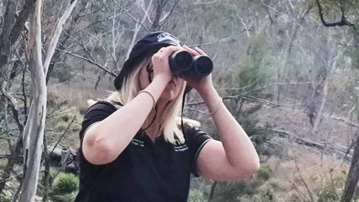 Candice looking through binoculars in the field