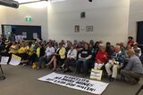 People sitting in protest at the new MidCoast council's first meeting