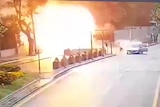 A video screen grab of an explosion on the side of a street. 