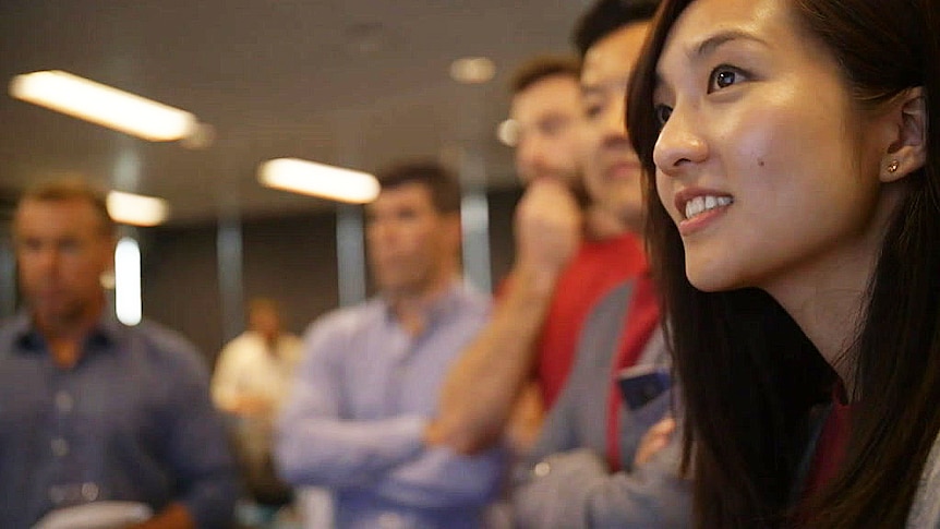 A woman smiles while others are blurred in the background