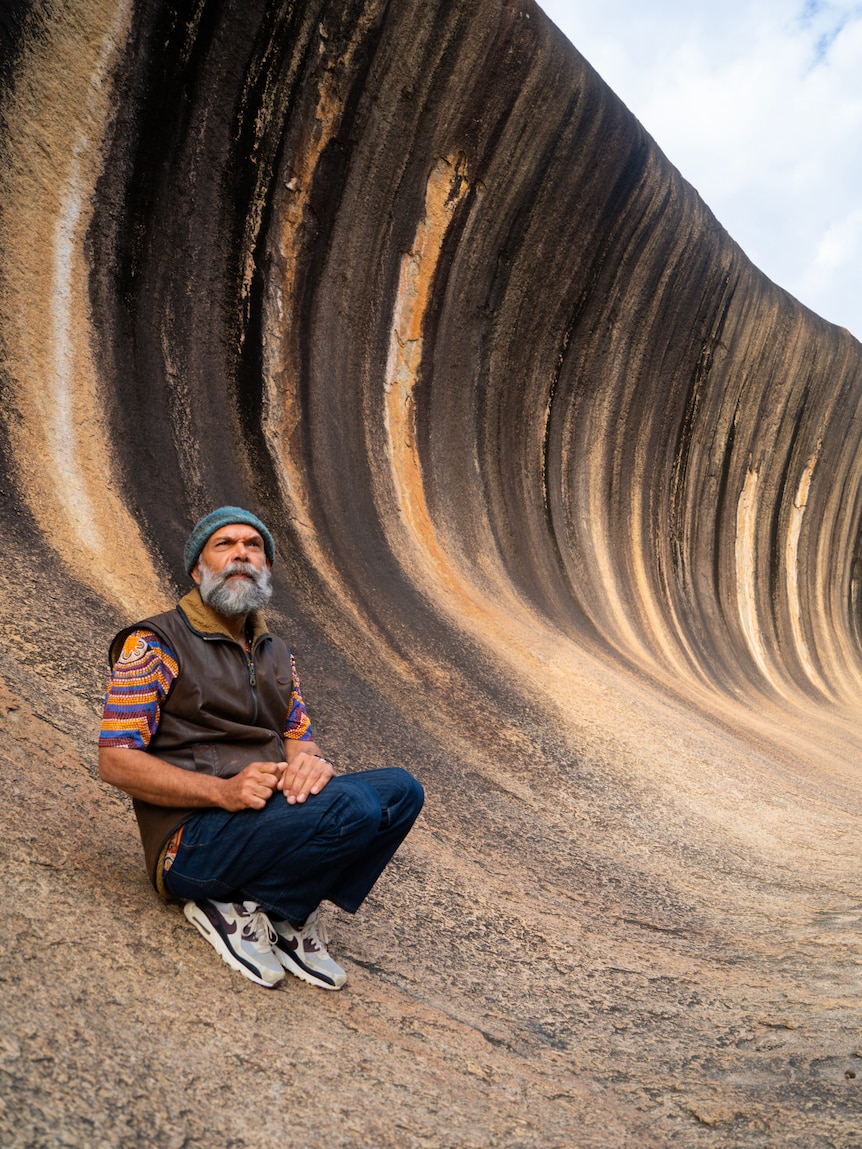 man in front of giant wave rock