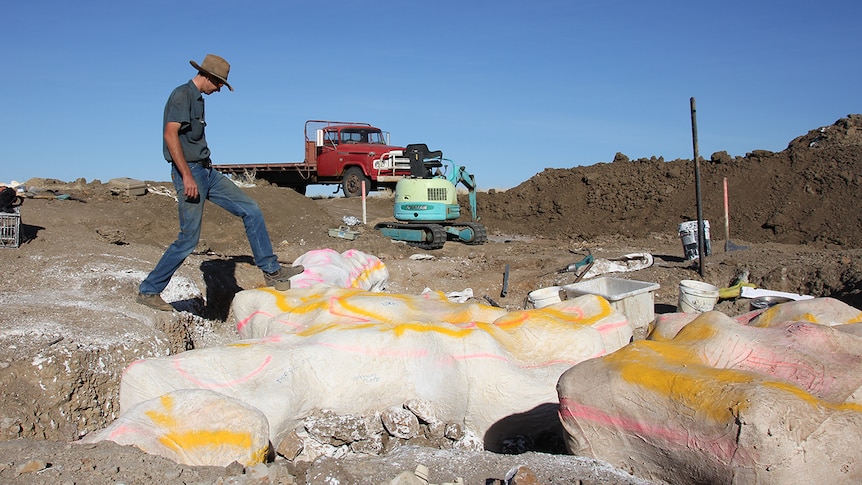 Bob Elliott leans his foot onto a dinosaur bone dug out of the ground at Winton property