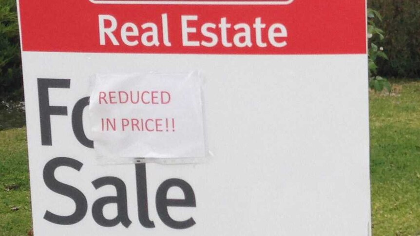 Sign saying price reduced on real estate for sale.