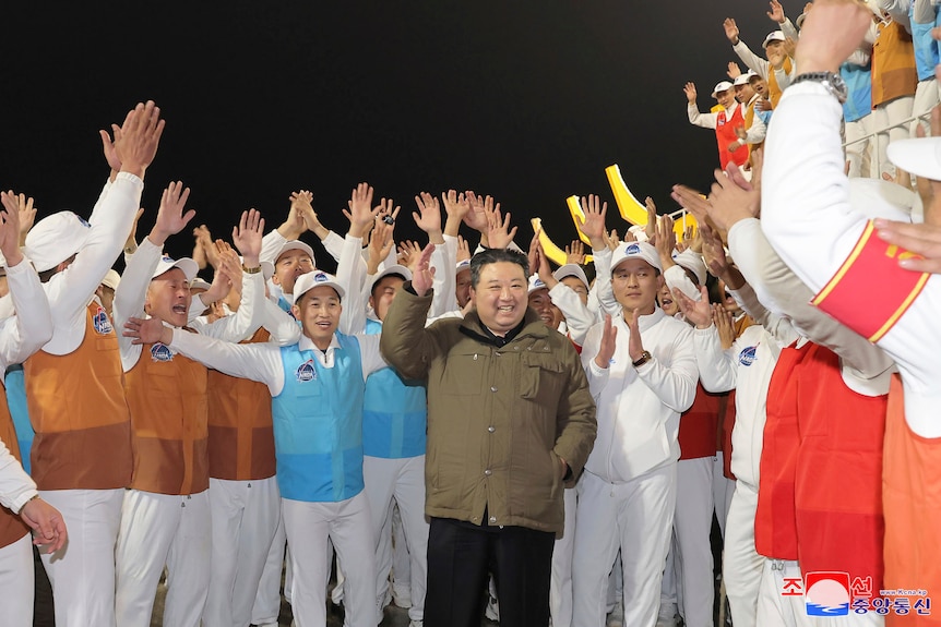 Kim Jong Un surrounded by a crowd of peopel cheering. 