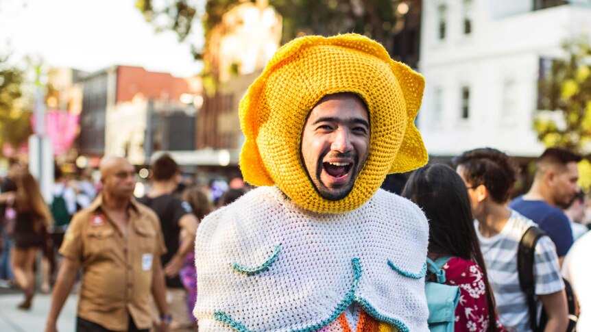 A man in a crochet costume laughs in a crowd