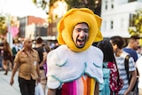 A man in a crochet costume laughs in a crowd