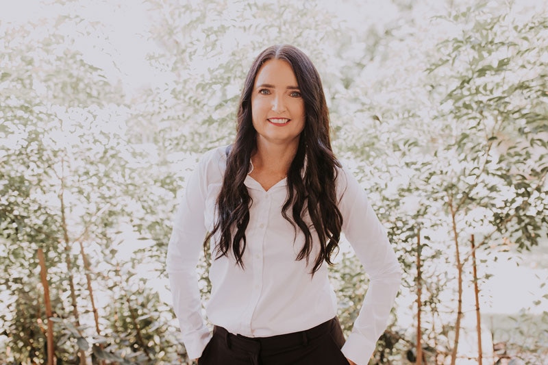 A young woman standing in front of a tree 