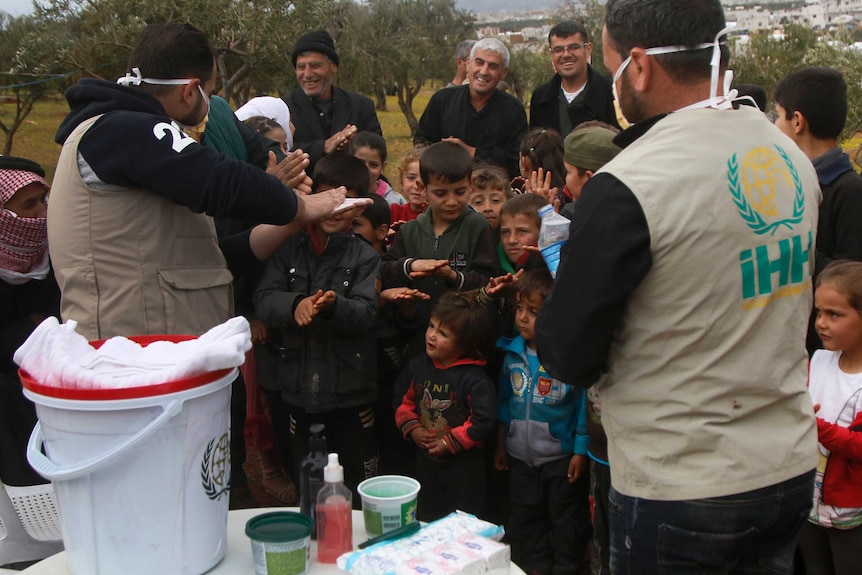 Aid workers of the group demonstrate to Syrian children how to properly wash hands.