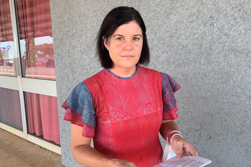 NT Health Minister Natasha Fyles holding a piece of paper, outside a building.