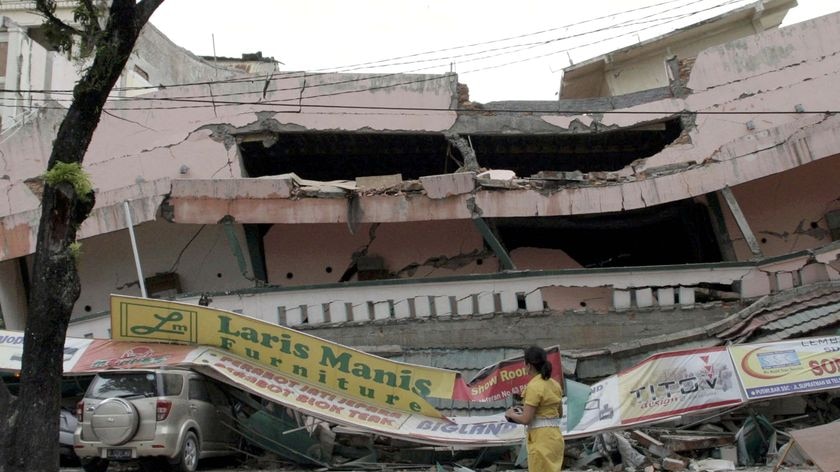 A woman walks in front of a collapsed shopping mall after an earthquake hit Padang