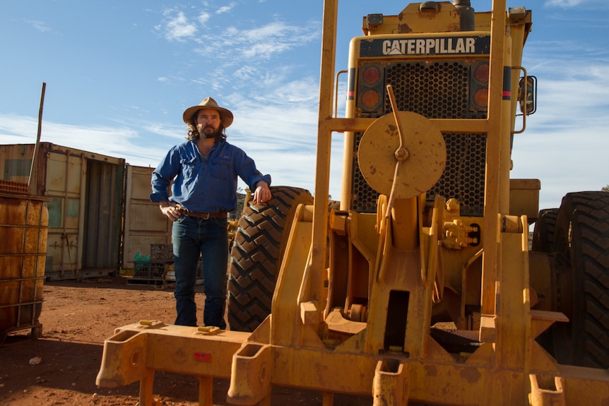 A man stands next to a bulldozer