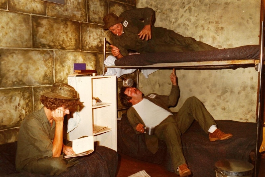 Three men on stage on bunk beds