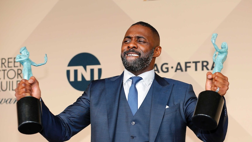 Idris Elbda holds up his two SAG awards