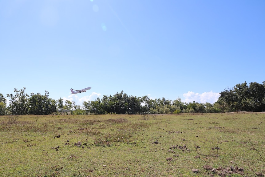 A field with a plane taking off in the background