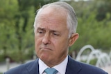 A frowning Malcolm Turnbull, wearing a suit and a light blue tie, stands outside Federal Parliament.