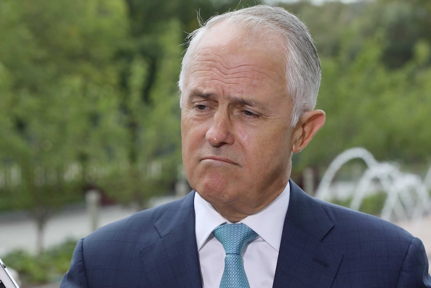 A frowning Malcolm Turnbull, wearing a suit and a light blue tie, stands outside Federal Parliament.