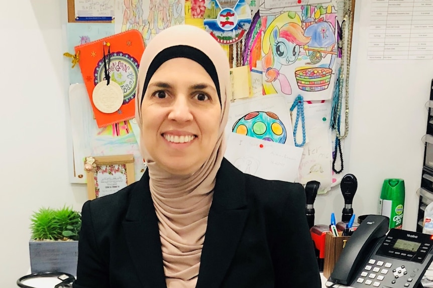 A woman smiling to camera with various art works in her background