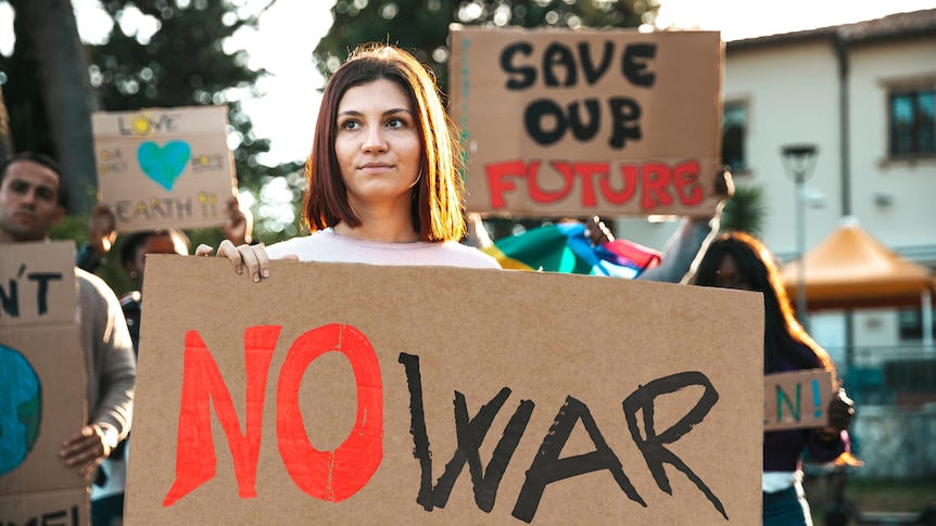 Young woman holding a placard that says no war at a protest