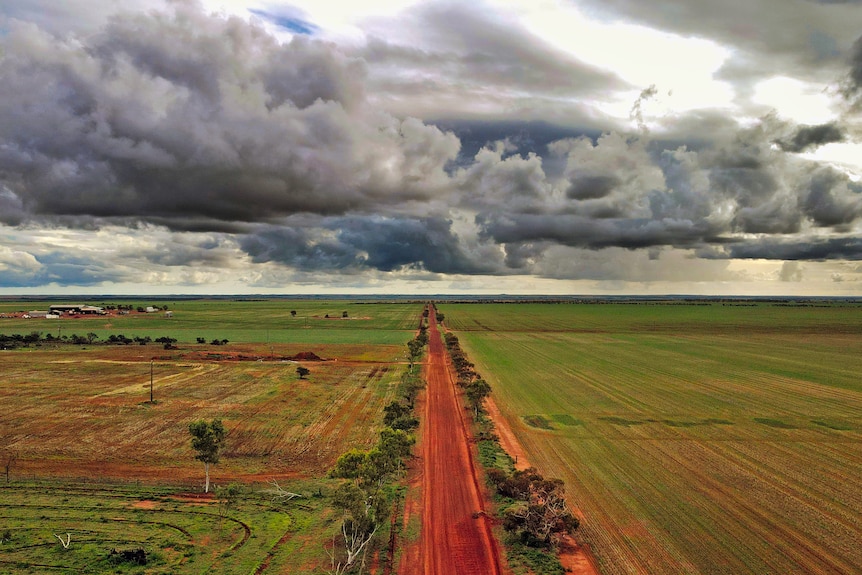 An aerial photo of a dirt road surrounded by green paddocks.