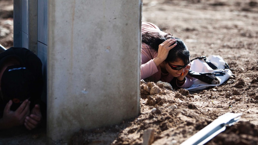 Israelis take cover as a siren sounds warning of incoming rockets in the southern town of Kiryat Malachi, November 15, 2012.