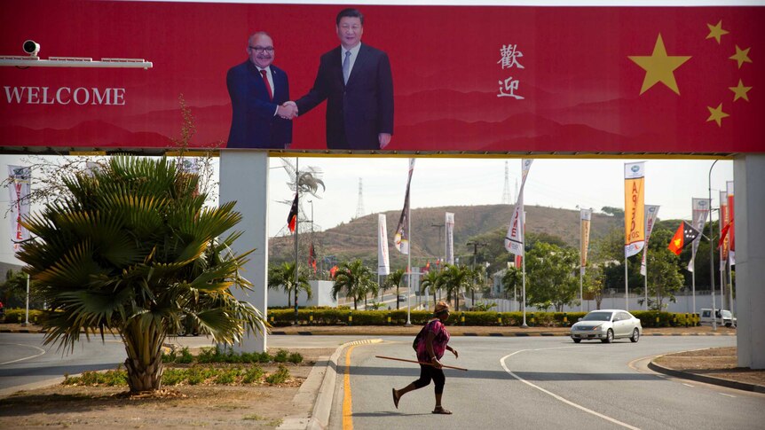 A woman crosses the street near a billboard commemorating the state visit of Chinese President Xi Jinping in Port Moresby.