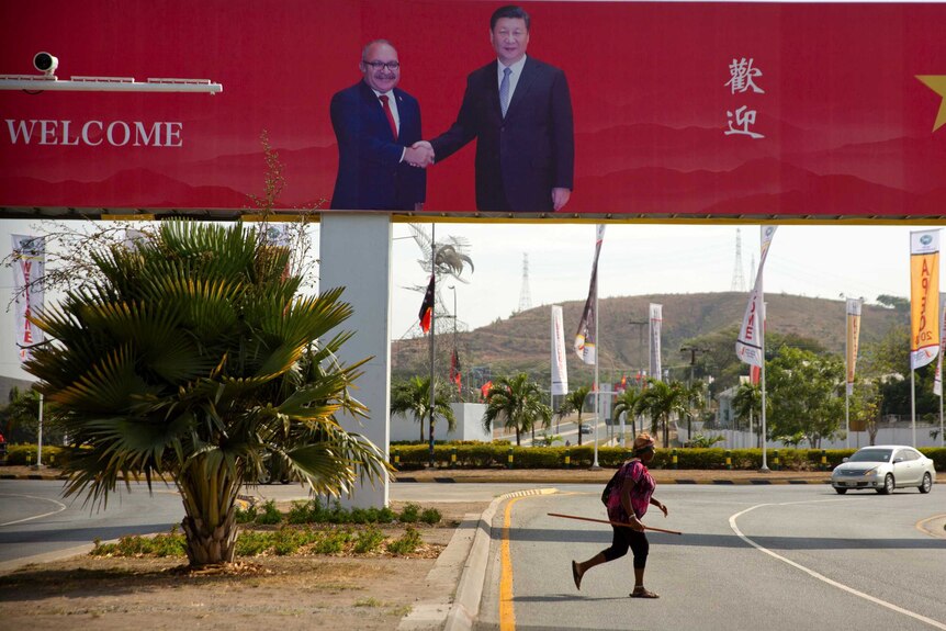 A woman crosses the street near a billboard commemorating the state visit of Chinese President Xi Jinping in Port Moresby.