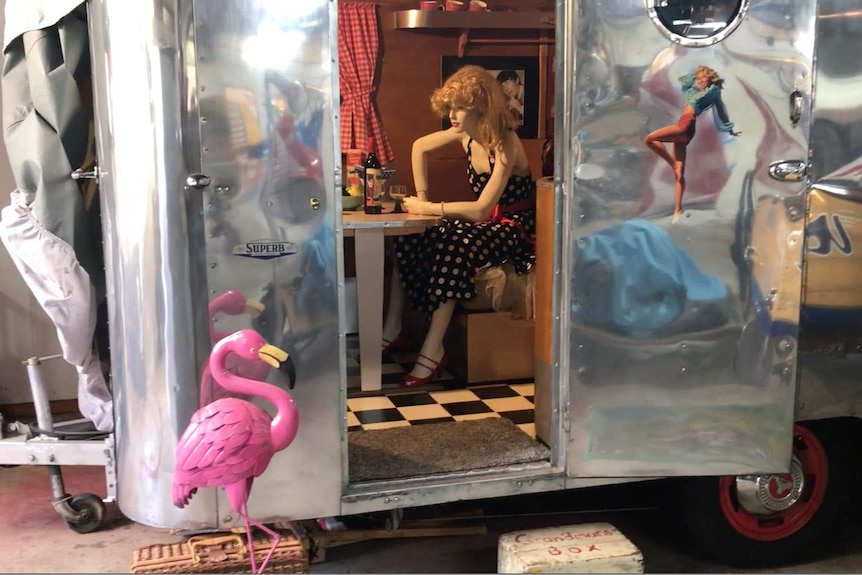 A fully reflective surface is on the 1956 Carapark caravan, door open with a mannequin dressed in '50s clothing