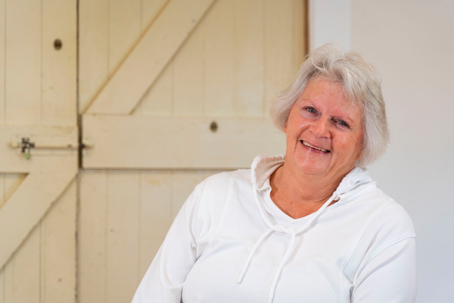 A woman with white hair and a white jumper, black leggings and tap shoes in a white room