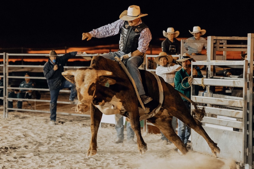 A bull rider in full flight at an outback rodeo.  