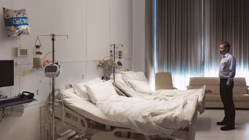 Colin Farrell stands facing an empty hospital bed in the poster for 2017 film The Killing of a Sacred Deer.