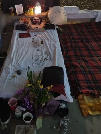 Teisha's friend lying next to her swag and memorial at Go Between Bridge